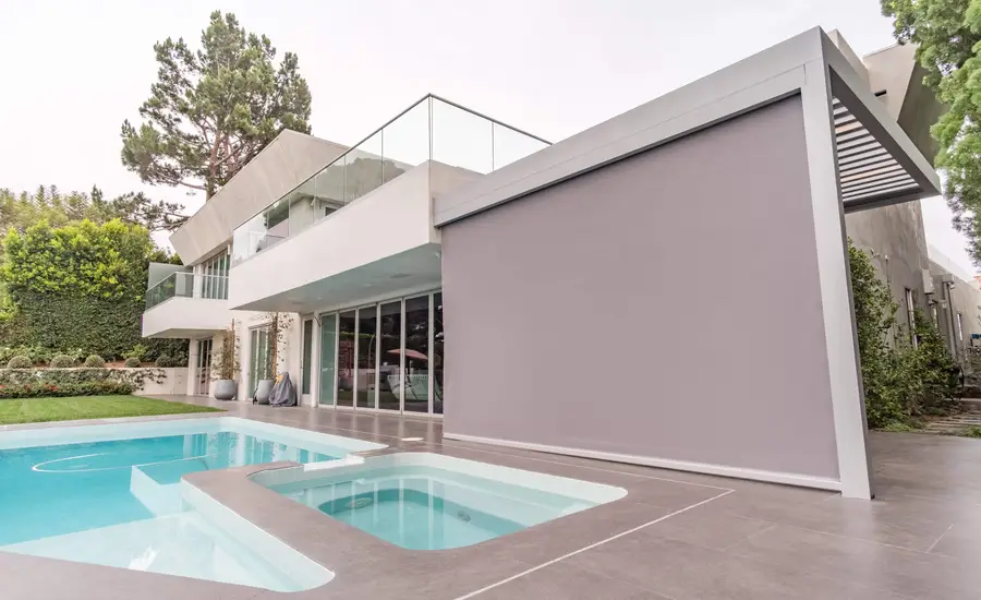 Exterior roller shade system, fully-lowered next to an outdoor pool.