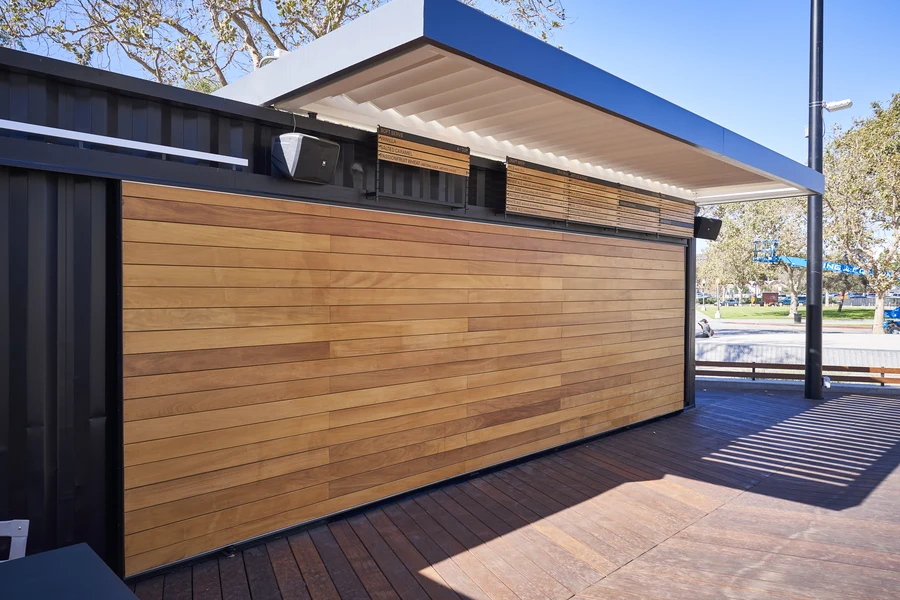 Wooden shutters installed at the entrance to an outdoor patio area on a sliding track.