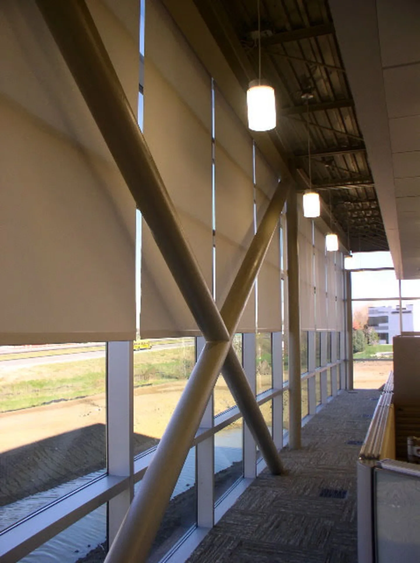 Hallway of an office with roller shades half-raised on all of the windows.