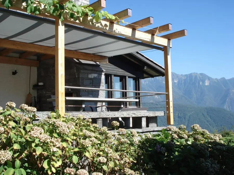 Ivy-covered patio shading structure with mountains in the background.