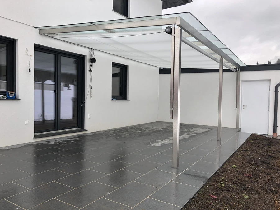 Patio shade structure with a glass top covering a marble patio.