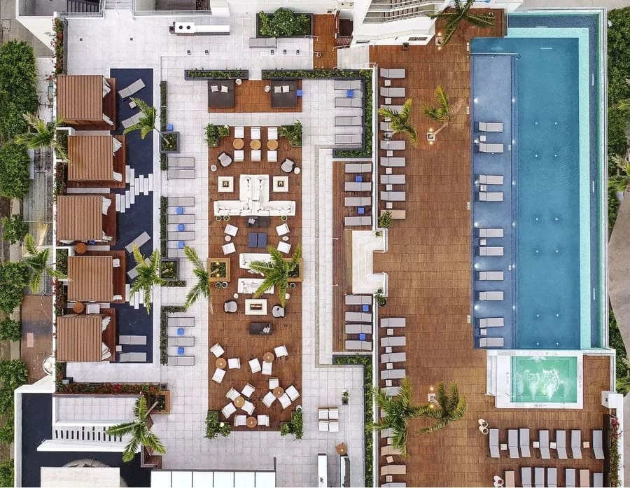 Aerial shot of a large pool deck with several wooden cabanas.