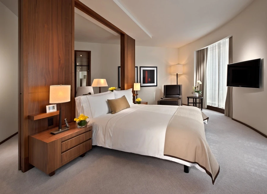 Wide shot of the primary bedroom of a suite in a Setai hotel.