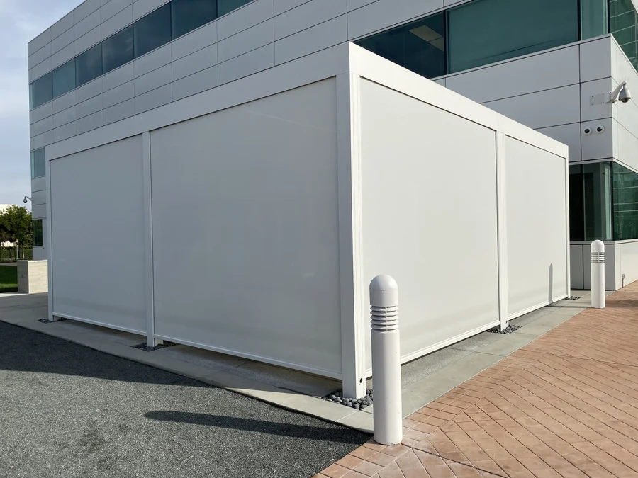 Fully-lowered roller shade system around an outdoor seating area at an office.